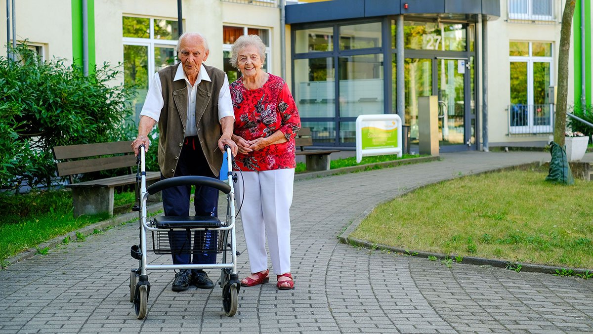 Spaziergang eines Ehepaares vor der Stationären Pflege der Seniorenresidenz Am Hufeisensee