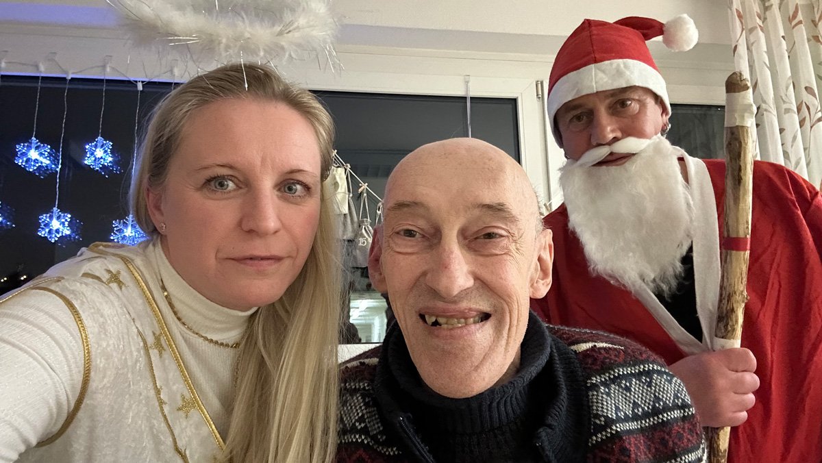 Im ProCurand Pflegestift Pfarrer Lukas in Cham stehen Nikolaus Christian Jaslovsky und Christkind Nicole Roith gemeinsam mit einem Bewohner und &uuml;berbringen die gef&uuml;llten Stiefel.