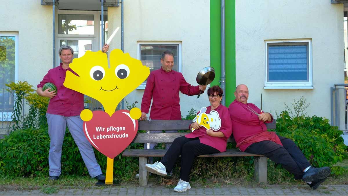 Das Küchenteam steht mit dem Ginkgo draußen vor dem Service-Wohnen der Seniorenresidenz Am Hufeisensee